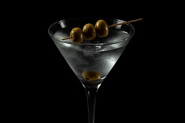 A cloudy Dirty Martini in a chilled martini glass with a pick of green olives, cold moody light.