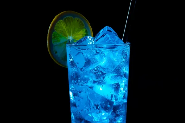 A tall electric-blue Electric Iced Tea over ice, glowing aqua, with a lemon wheel and a straw against a dark background.