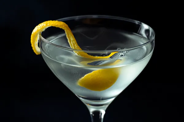 A Vesper Martini in a chilled coupe glass with a large lemon twist, cold crisp elegant light.
