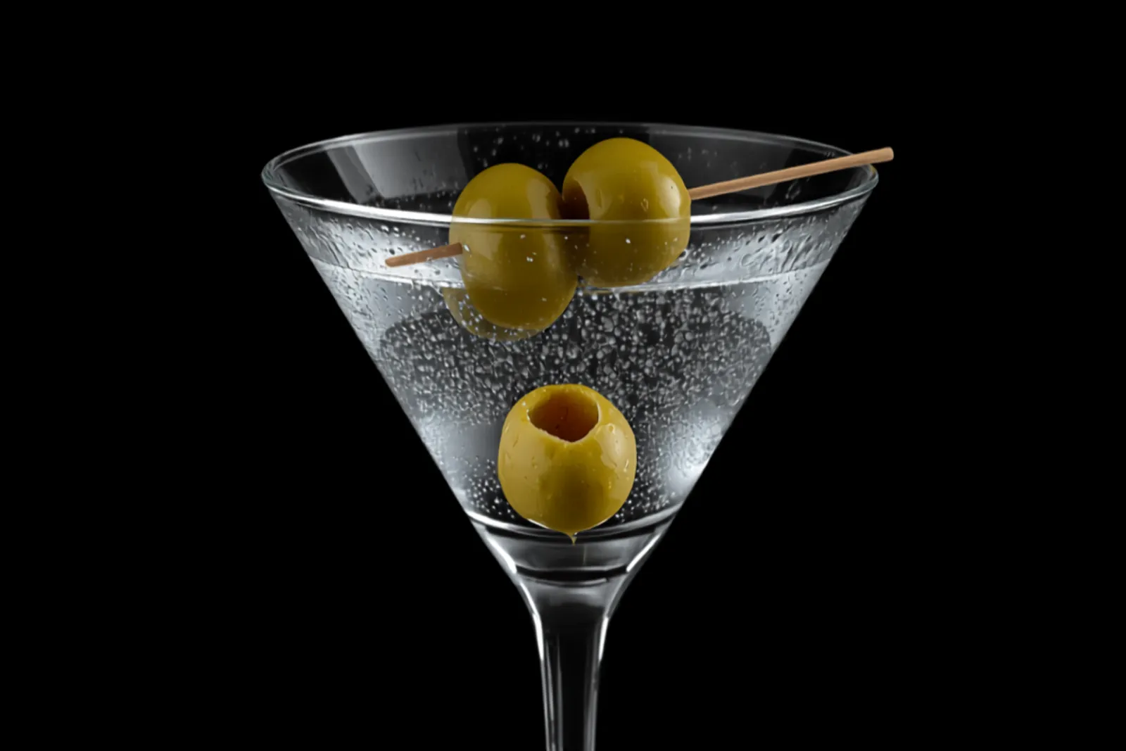 A crystal-clear vodka Martini in a chilled martini glass with two green olives on a pick, cold crisp light.